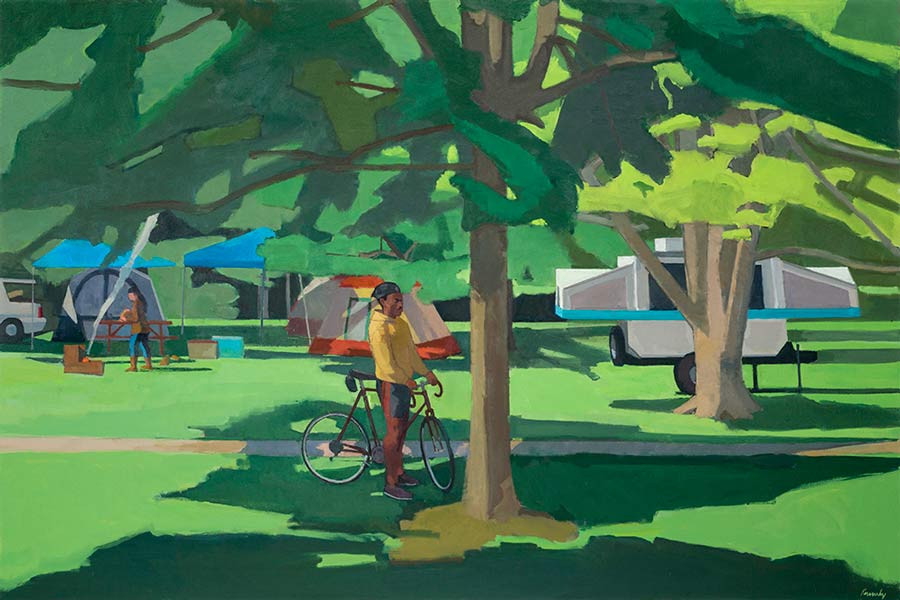 Man standing next to his bicycle under a tree, looking at camp ground.